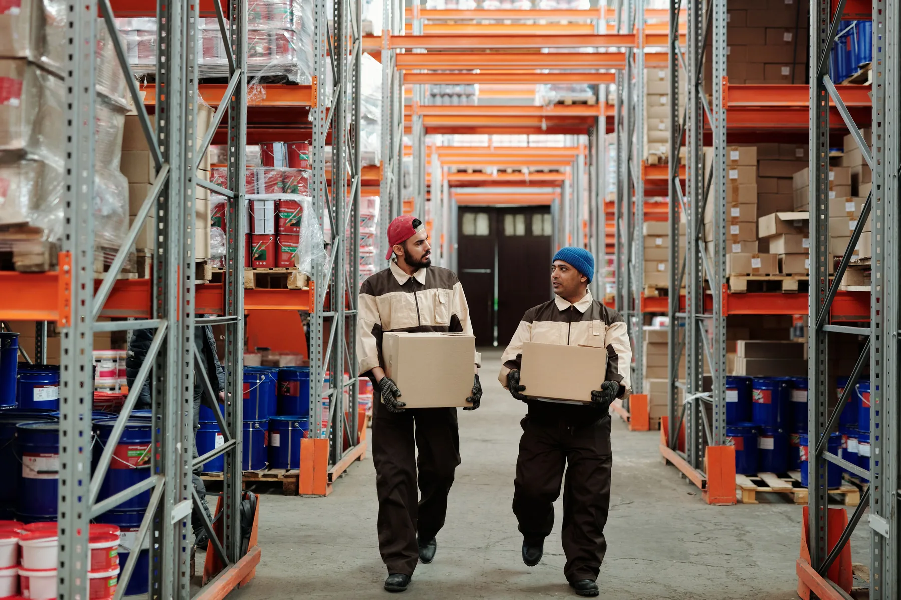 Warehouse employees carrying boxes between storage racks